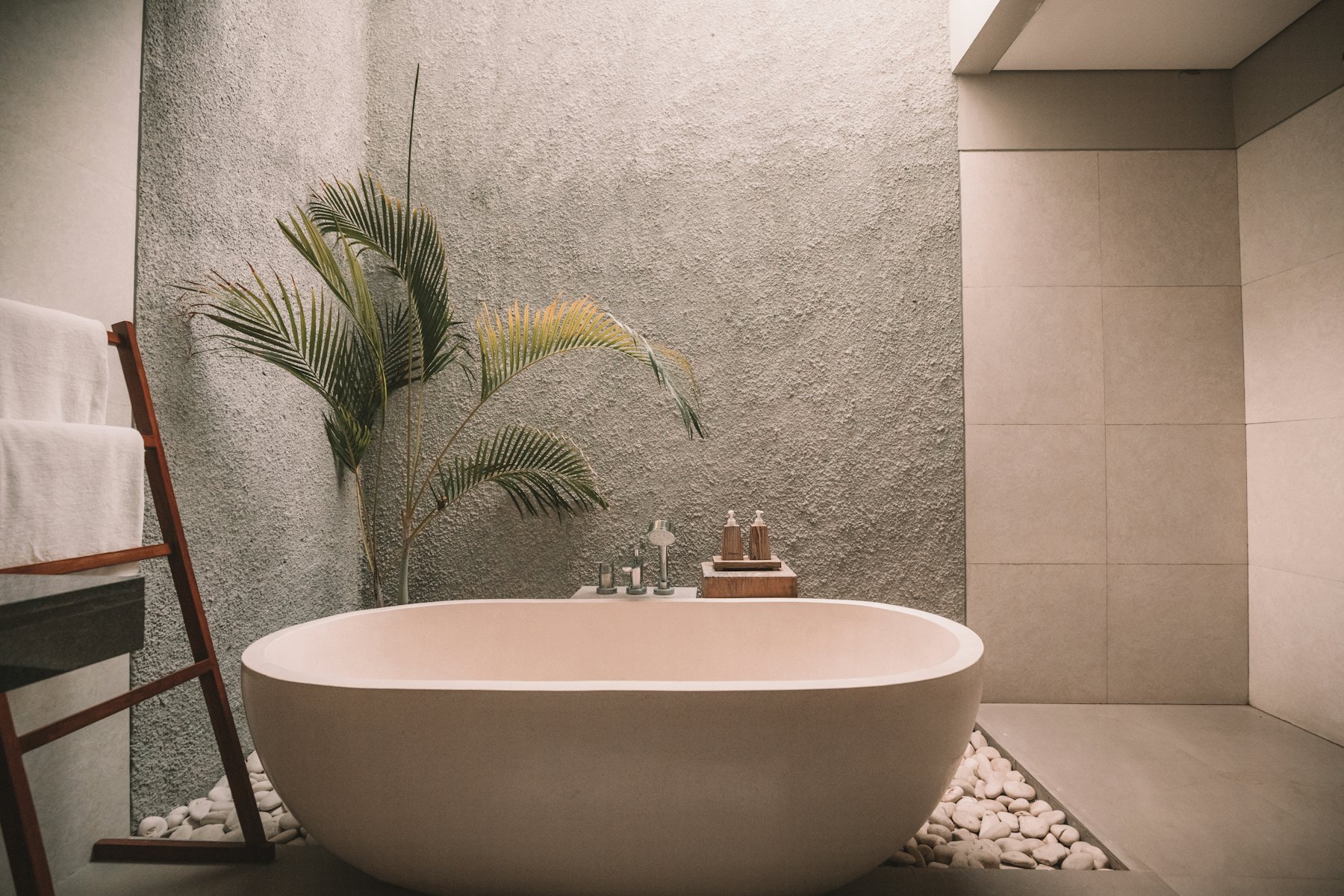 Spa bathroom with a freestanding stone bath and warm neutral surfaces
